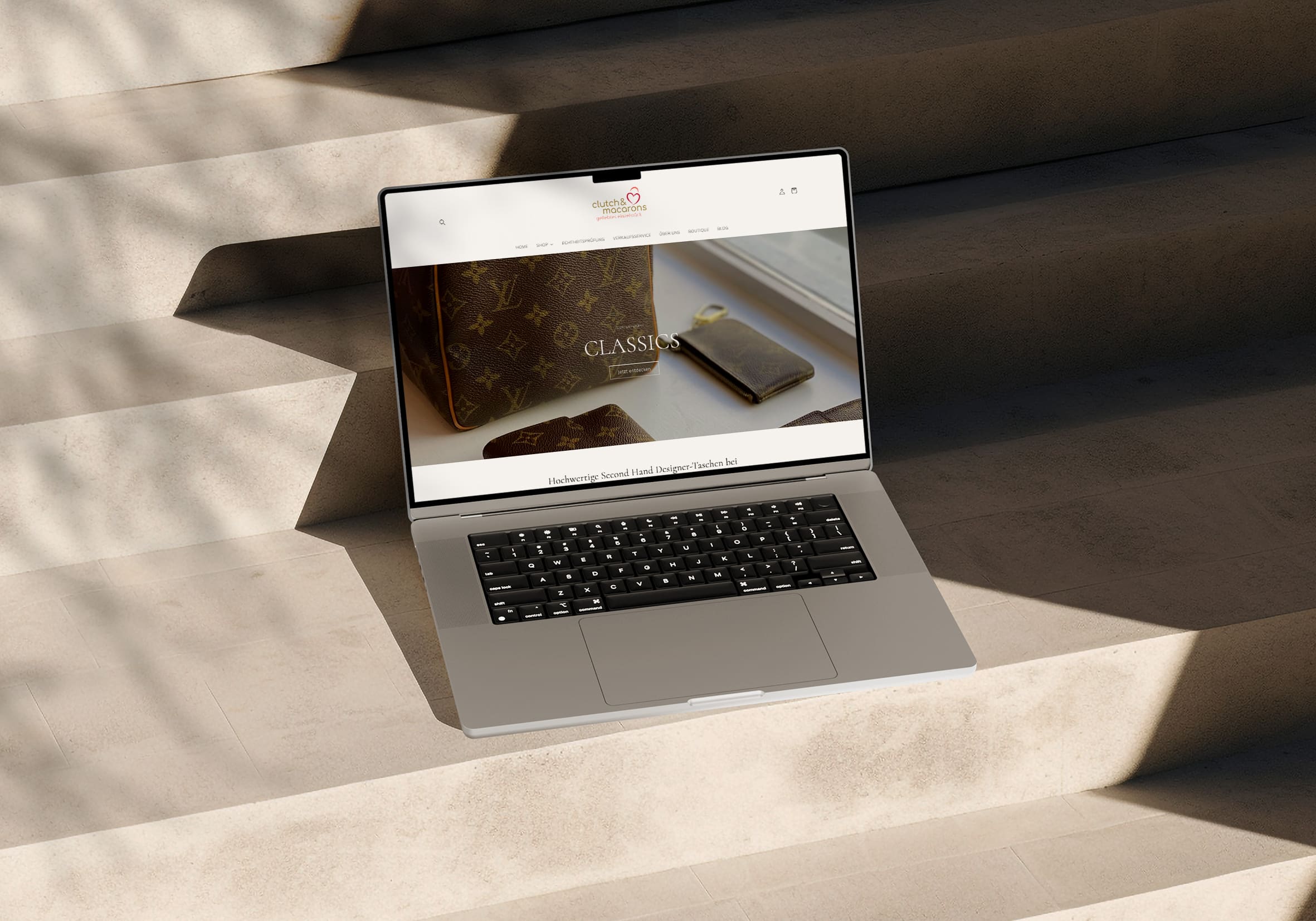 Laptop mit geöffneter Website von Clutch & Macarons auf einer Treppe. Hochwertige Second-Hand Designer-Taschen mit Echtheitsprüfung.